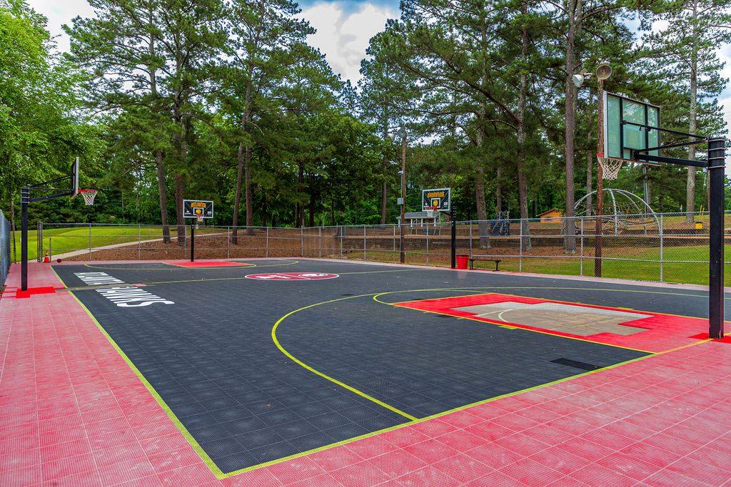 Outdoor-basketball-court-with-red-and-black-surface-surrounded-by-trees